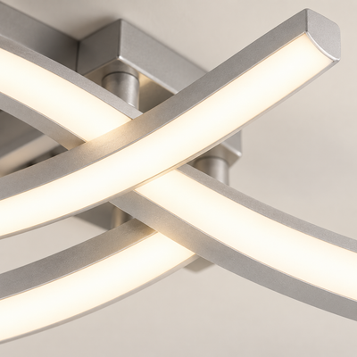 Détail rapproché des bandes courbes du plafonnier Arcéa, avec bords en aluminium argenté satiné et diffuseurs blancs allumés.