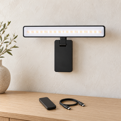 Applique murale Lumio noire fixée sur un mur clair, avec télécommande noire et câble de recharge USB-C posés sur une console en chêne clair.