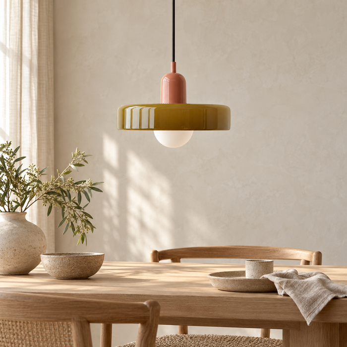 Suspension à dôme de verre teinté vert olive nervuré au-dessus d'une table en chêne clair dans une salle à manger japandi lumineuse.