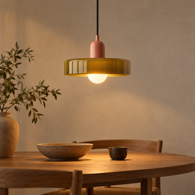 Suspension à dôme de verre vert olive nervuré allumée au-dessus d'une table en bois, lumière chaude dans une pièce japandi du soir.