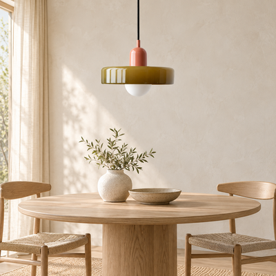 Suspension à dôme de verre vert olive nervuré au-dessus d'une table ronde en chêne clair entourée de chaises en cannage.