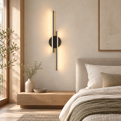 Applique murale Sila noire à deux barres verticales, allumée sur un mur clair dans une chambre Japandi avec bois clair et linge naturel.