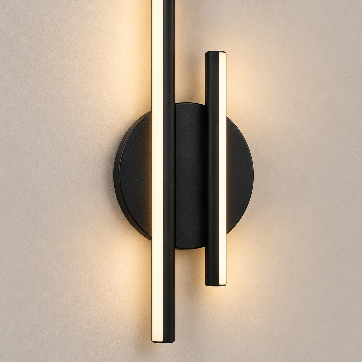 Gros plan de l’applique Sila avec platine ronde noire, barres en aluminium noir et diffuseurs blancs lumineux sur un enduit clair.